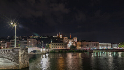 Fototapeta premium Panorama showing night timelapse of Lyon's cityscape with the red suspension footbridge over the Saone River. France