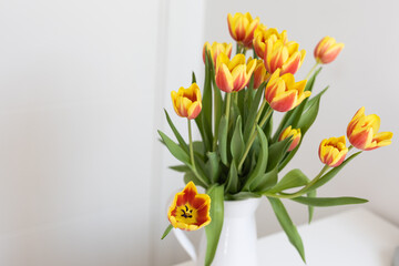 Tulip bouquet in a white vase on a table, copy space. Concept of nature, home decor and spring