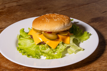 A juicy cheeseburger with a sesame seed bun, melted cheese, beef patty, and lettuce on a white...