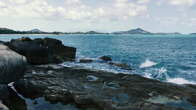 The restless waves of the Gulf of Thailand beat against the rocks