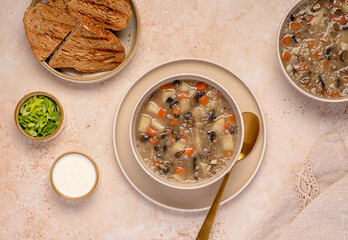 Food photography of mushrooms soup with barley and vegetables, carrots; potatoes, spring onion, cream, toasted bread, vegetarian healthy food