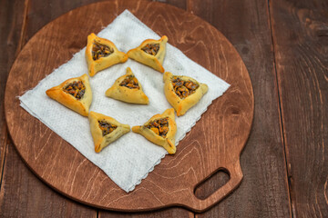 Sweet pastries triangular gomentashi ears of Haman for Purim on a wooden board