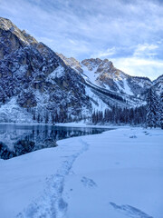 Lake Braies with its snowy rocky mountains clear blue water that reflects the mountain