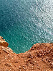 coast of the sea with orange cliffs overlooking the bright turquoise ocean by Nazare in Portugal in october. Reflection of light over the waves 