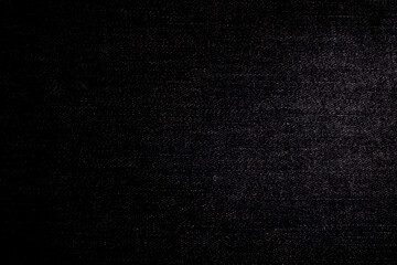 A close-up of a textured, denim, dark fabric with subtle shimmering hues creating an elegant and rich background suitable for a variety of designs.