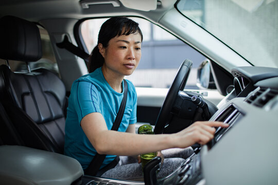 Asian woman in sportswear using car touchscreen navigation