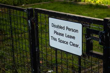 A sign that says do not block the space, as this is the residence of a person with a disability. A sign is hanging on the entrance gate.