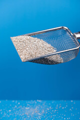 Clumping Cat Litter Scoop on Blue Background. Feline Care Routine: cleaning a cat kitty litter box and adding new absorber granules.