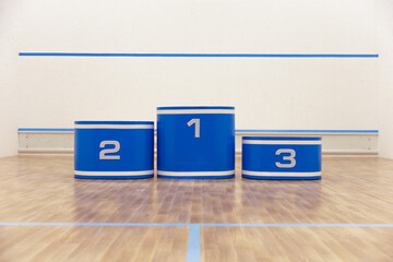 A squash court with a podium displaying the champions' prize places.