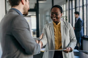 Two business professionals standing in a modern office, collaborating on a tablet