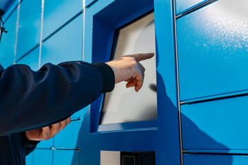 Man Using Self-Service Package Locker – Receiving or Sending a Parcel via Automated Terminal....