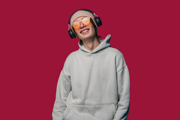 Young person in stylish headphones and sunglasses stands out against a bright red background