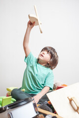 A young boy is playing with a toy airplane, holding it up high