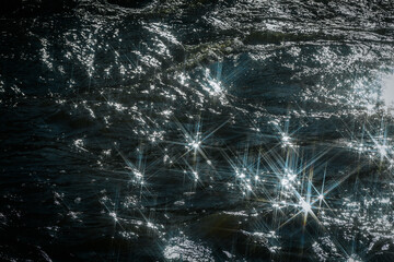 Sunlight reflects off flowing water, creating a dazzling starburst effect. The contrast between...