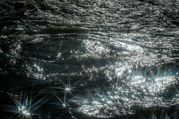 Sunlight reflects off flowing water, creating a dazzling starburst effect. The contrast between...