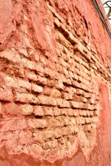 A dilapidated wall with peeling plaster through which bricks are visible