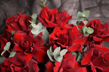 Bouquet of red roses with eucalyptus on black dark relief background. Flower arrangement. Close up....