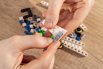 Young man collects the parts of a construction kit. Hobbies for adults. Man connects the parts of the constructor
