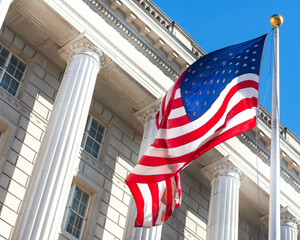A large American flag flies against a blue sky in front of a columned building.