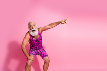 Photo of crazy funky cheerful senior man showing empty space isolated on pink color background