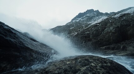 Fototapeta premium Ocean waves crash against rugged rocks under a dim, misty sky, capturing nature's powerful, untamed spirit in a dramatic coastal scene.