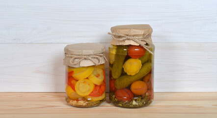 Glass Jars Of Preserved Vegetables on a table and wall.