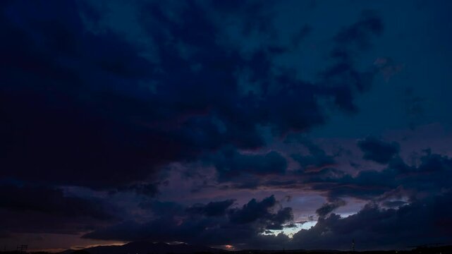 Timelapse of an incredibly colourful sunset with clouds all over and houses visible on the ground.