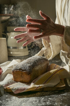 Rustic bread baking with flour dusting and hands in motion