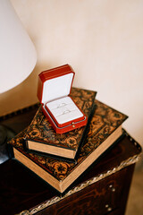 Pair of wedding rings in a box lie on a stack of books on the nightstand
