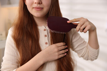 Teenage girl brushing her hair at home, closeup