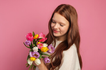 Fototapeta premium Beautiful teenage girl with bouquet of tulips on pink background