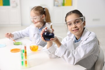 Children doing chemical experiment at desk indoors, selective focus