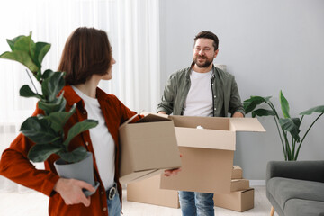 Moving day. Happy couple with their belongings in new home, selective focus