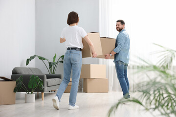 Moving day. Happy couple with cardboard boxes in their new home