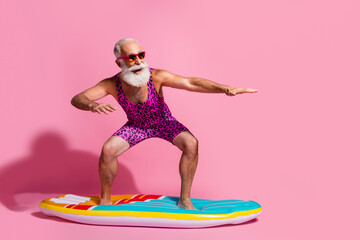 Photo of crazy optimistic grandfather wear swimsuit resort surfing wave isolated on pink color background