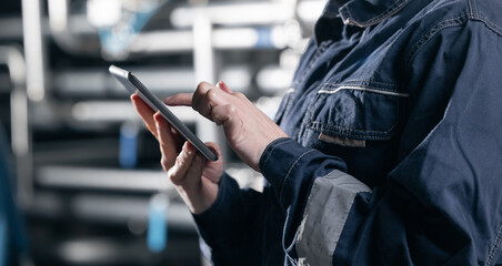 Concept food industry banner. Factory worker inspecting production line tanker in of dairy factory with computer tablet