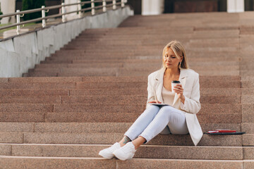 Businesswoman Relaxing on Outdoor Steps with Coffee and Tablet