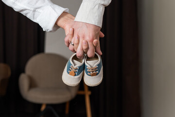 Expecting parents hold tiny blue baby shoes as they prepare for new arrival in cozy indoor setting