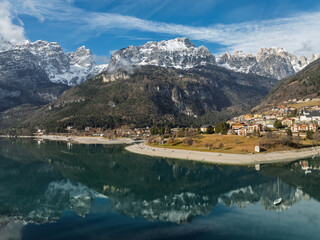 Aerial drone view of Lake Molveno, beautiful lake in Italy. Lake in dolomites from drone in winter. Lake Molveno in Italy. Sailboat, yacht on crystal clear lake in the Brenta Dolomites