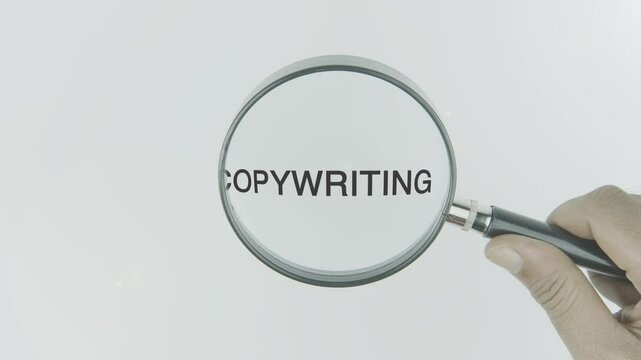 Copywriting text or word highlighted by a magnifying glass in a hand on a white background, symbolizing persuasive writing, advertising, and content creation