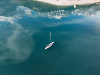 Aerial drone view of Lake Molveno, beautiful lake in Italy. Lake in dolomites from drone in winter. Lake Molveno in Italy. Sailboat, yacht on crystal clear lake in the Brenta Dolomites