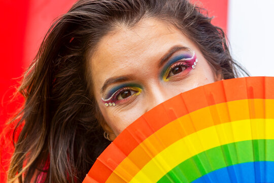 Colorful LGBTQIA+ dancer with pride flag fan and makeup