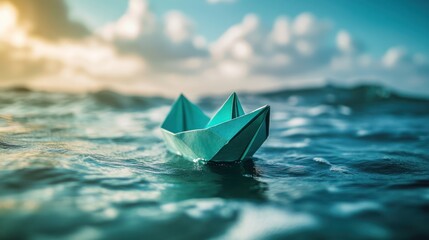 Obraz premium Small teal paper boat floats on blue ocean waves under a cloudy sky.