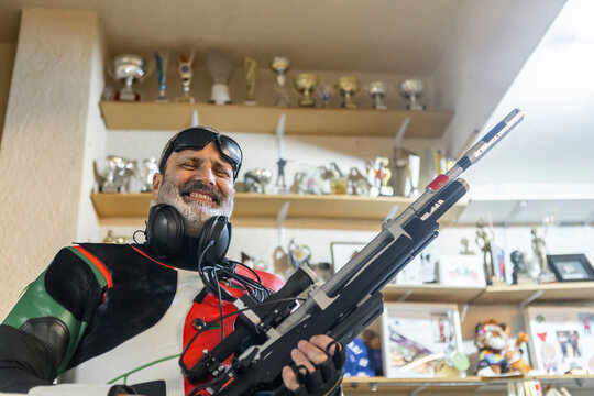 Blind athlete holding rifle in room of trophies
