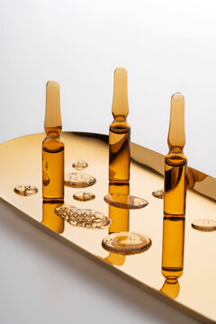 Cosmetic ampoules with anti-aging serum on golden background