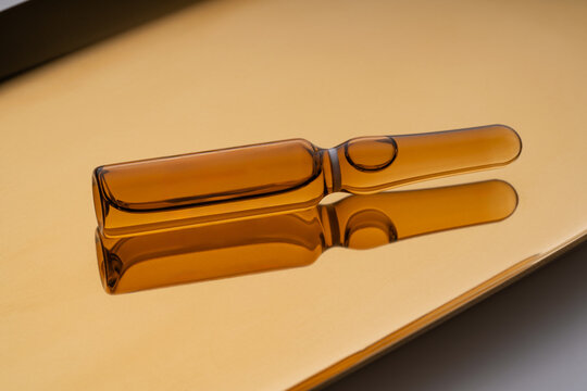 Cosmetic ampoules with anti-aging serum on a reflective surface