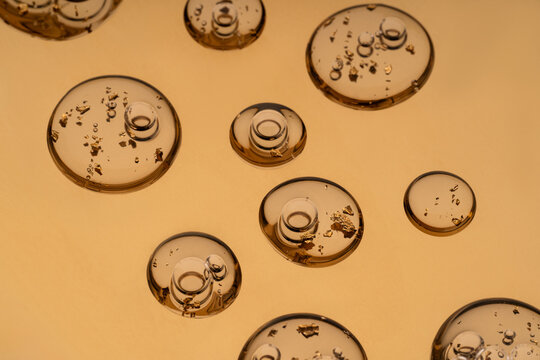 Close-up of anti-aging serum with golden flakes on yellow backdrop