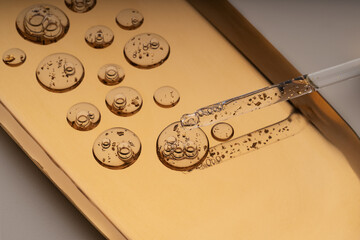 Golden particles in anti-aging facial serum on gold tray
