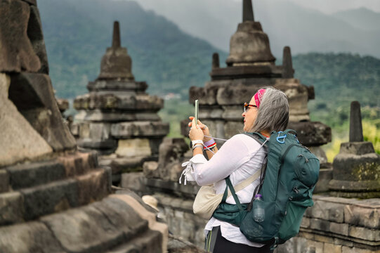 Anonymous mature female tourist photographing at Borobudur Temple