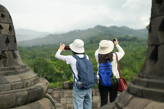 Back view of unrecognizable tourists at Borobudur Temple, capturing nature